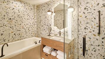 Un baño moderno con una bañera independiente, un tocador con espejo e iluminación, y una cabina de ducha de vidrio.