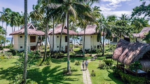 Een resort met rieten huisjes, een pad in het midden en weelderige begroeiing.