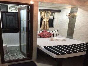 Una habitación de hotel con cama, zona de ducha y baño.