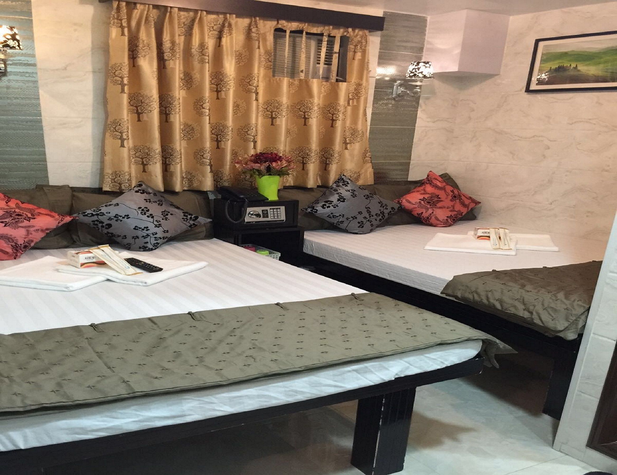 A hotel room with two beds, a small table, a telephone, and a vase with flowers.