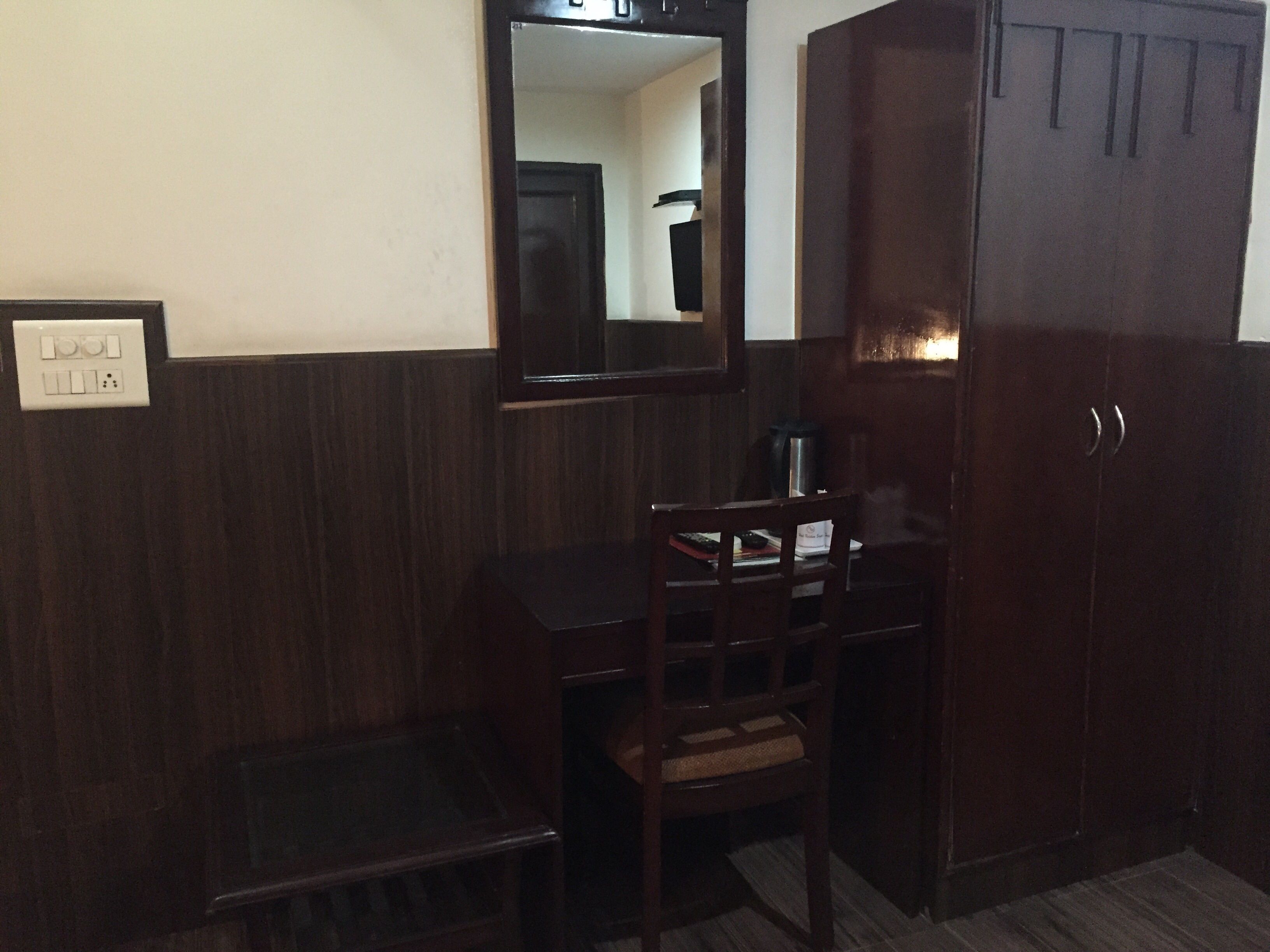 Une pièce comprenant un bureau en bois, une chaise, un miroir et une armoire.