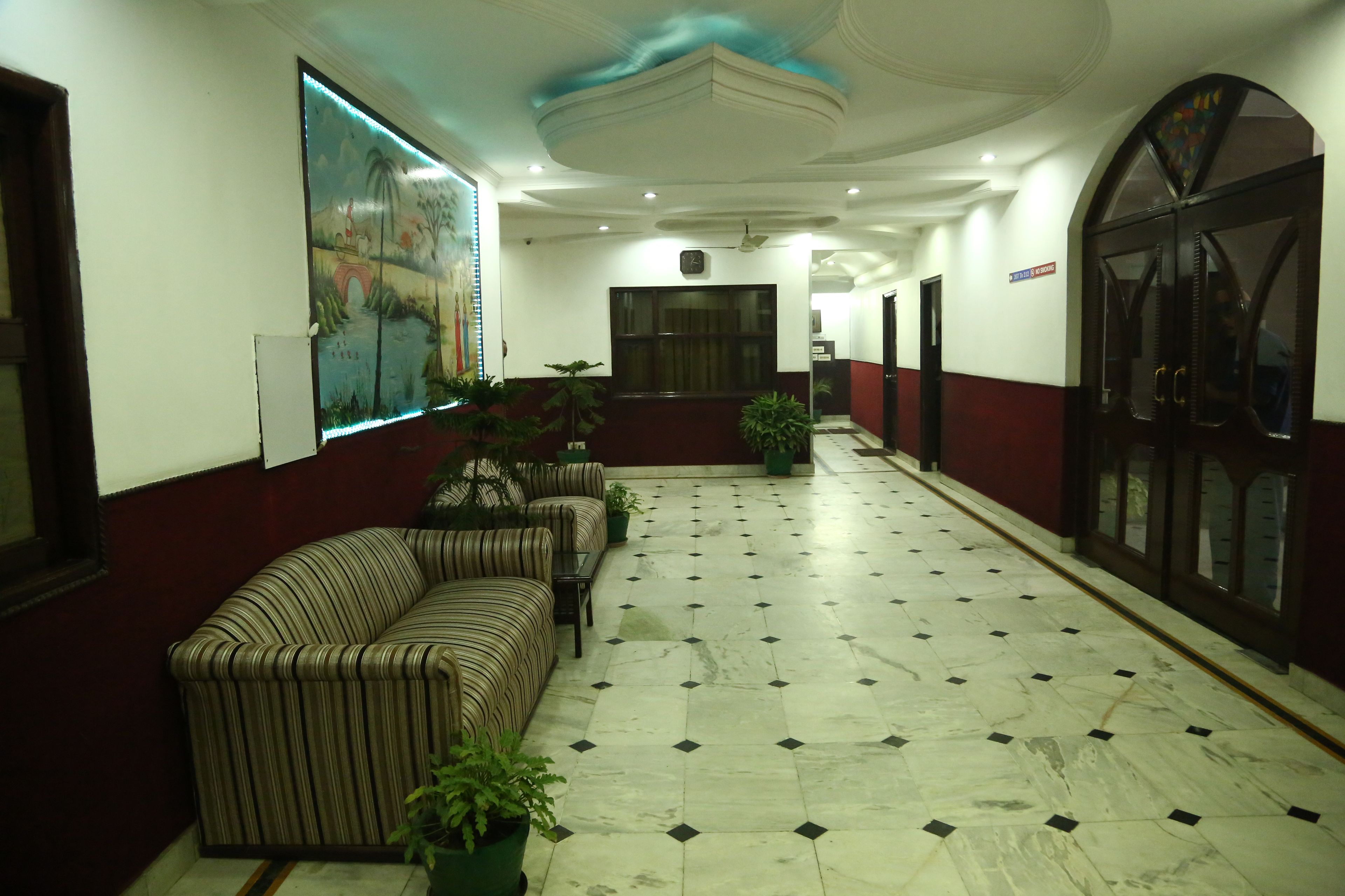 A hotel lobby with a check-in counter, seating area, and a large mural on the wall.