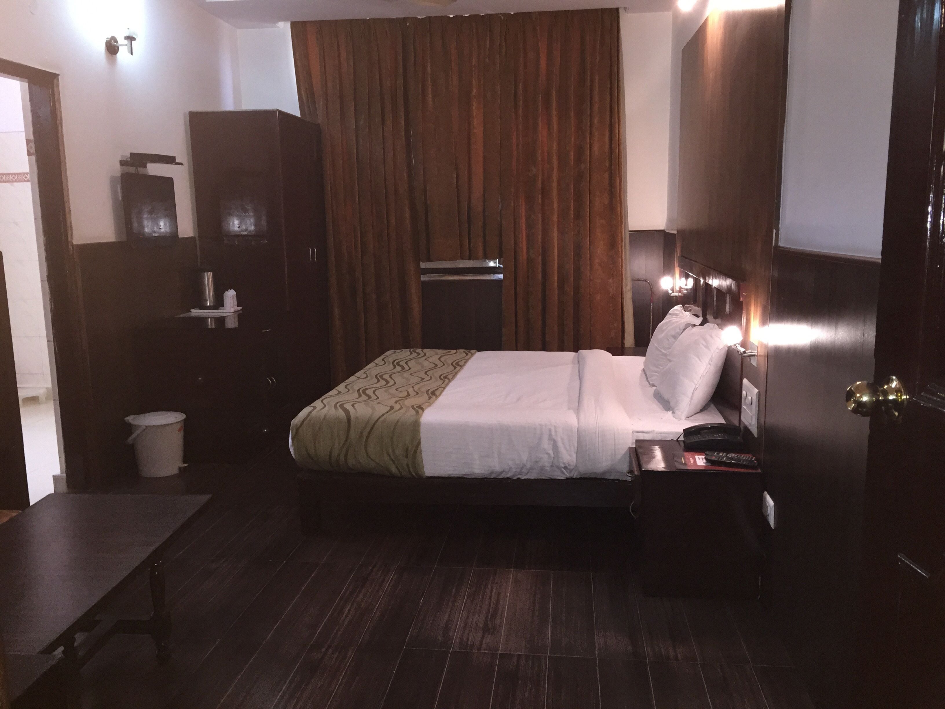 A hotel room with a bed, bedside table, and a wardrobe.