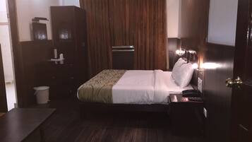 A hotel room with a bed, bedside table, and a wardrobe.