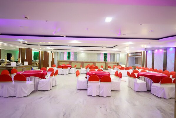 Un salón de banquetes con mesas redondas cubiertas con manteles blancos y sillas rojas.