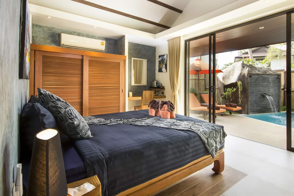 Ein Schlafzimmer mit einem großen Bett und einer Schiebetür zu einem Poolbereich.