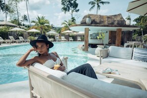 A poolside lounge area with a sofa, a table, and a drink. - Khwan Beach Resort - Pool Villas and Glamping - Adults Only (Koh Samui)
