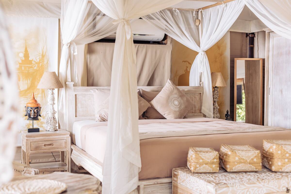 Ein Schlafzimmer mit Baldachinbett, Nachttischen und Zierkissen.