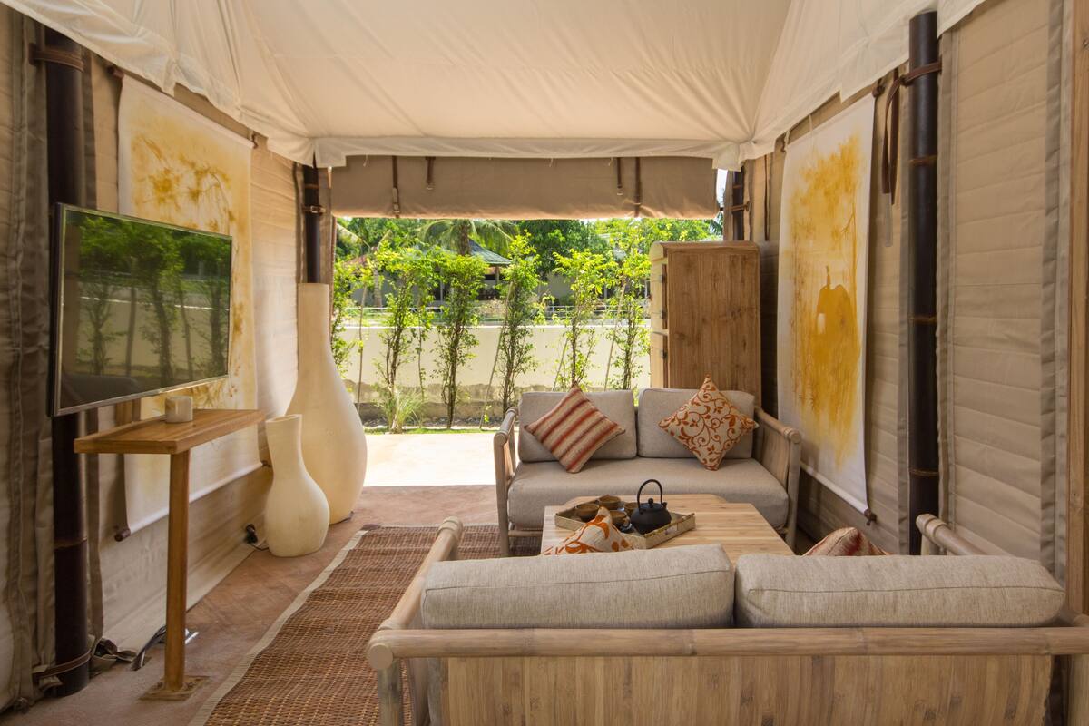 Ein gemütliches Interieur mit einer Couch, einem Fernseher und einem großen Fenster mit Blick auf Grünflächen.