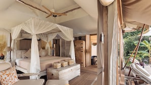 Une chambre spacieuse avec un lit à baldaquin, un coin salon doté d’un banc rembourré et une armoire en bois.