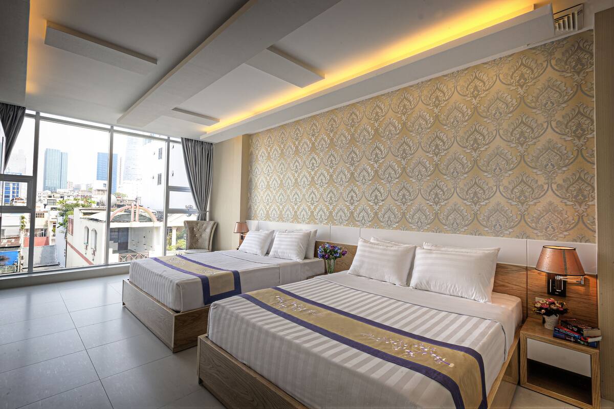 Ein Hotelzimmer mit zwei Betten, einem großen Fenster mit Blick auf die Stadt und einer Dekoration an der Wand.