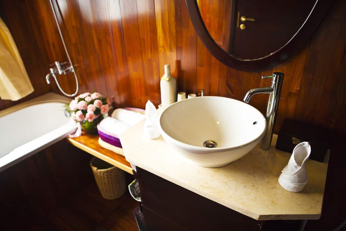 A bathroom with a white sink, a mirror, and wooden paneling.