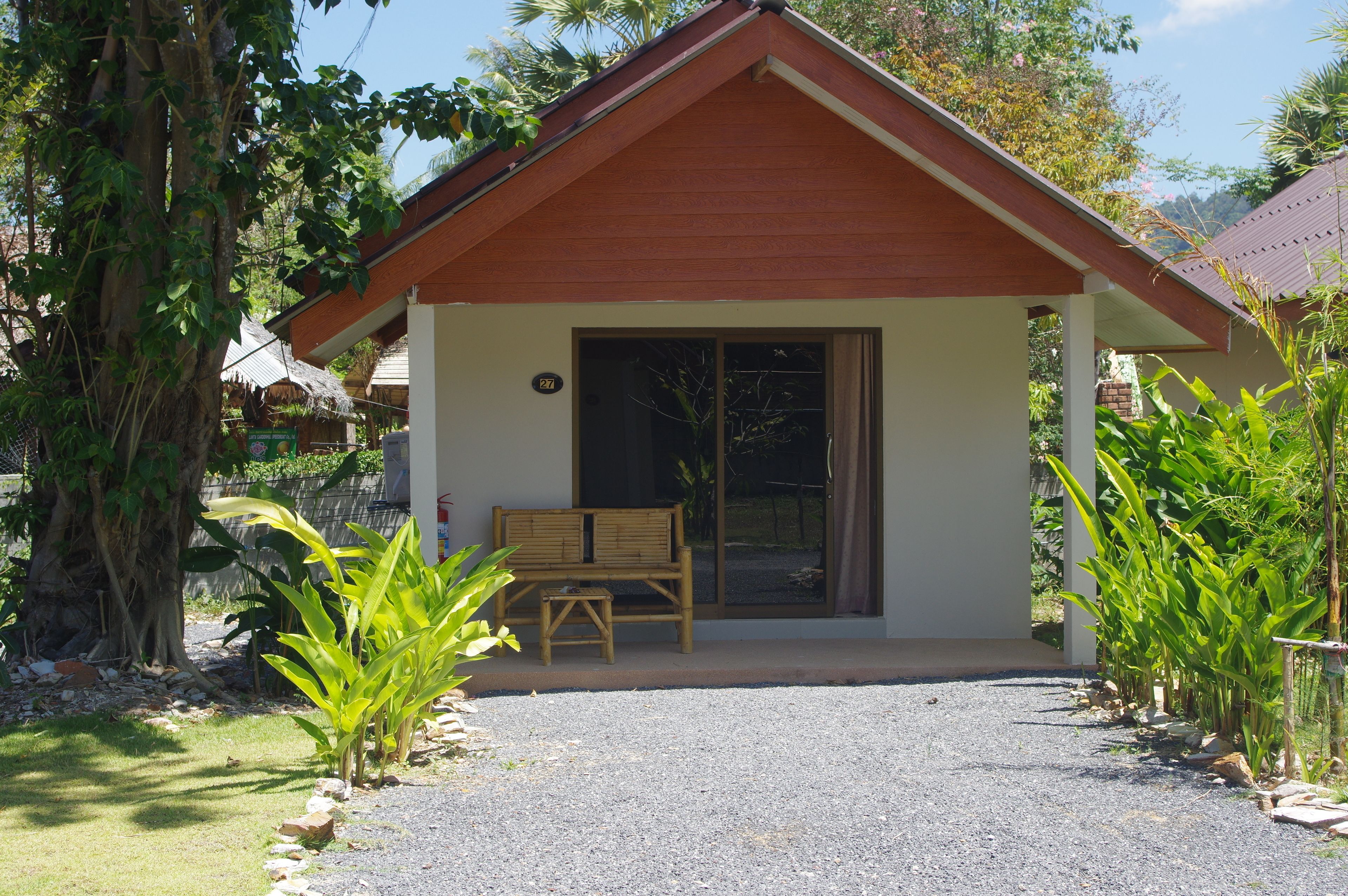 A small building with a wooden bench outside, surrounded by greenery.
