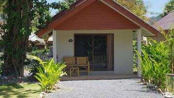 A small building with a wooden bench outside, surrounded by greenery.