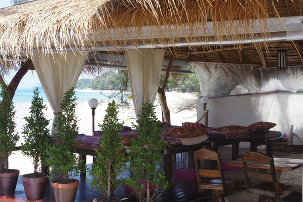 Un espacio al aire libre cubierto con vistas a la playa, plantas en macetas y mobiliario de madera.