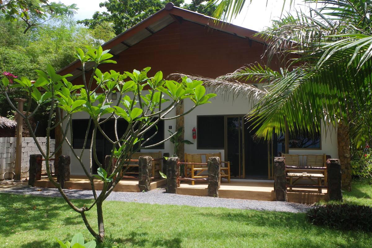 A building with a wooden porch, stone pillars, and a thatched roof structure.