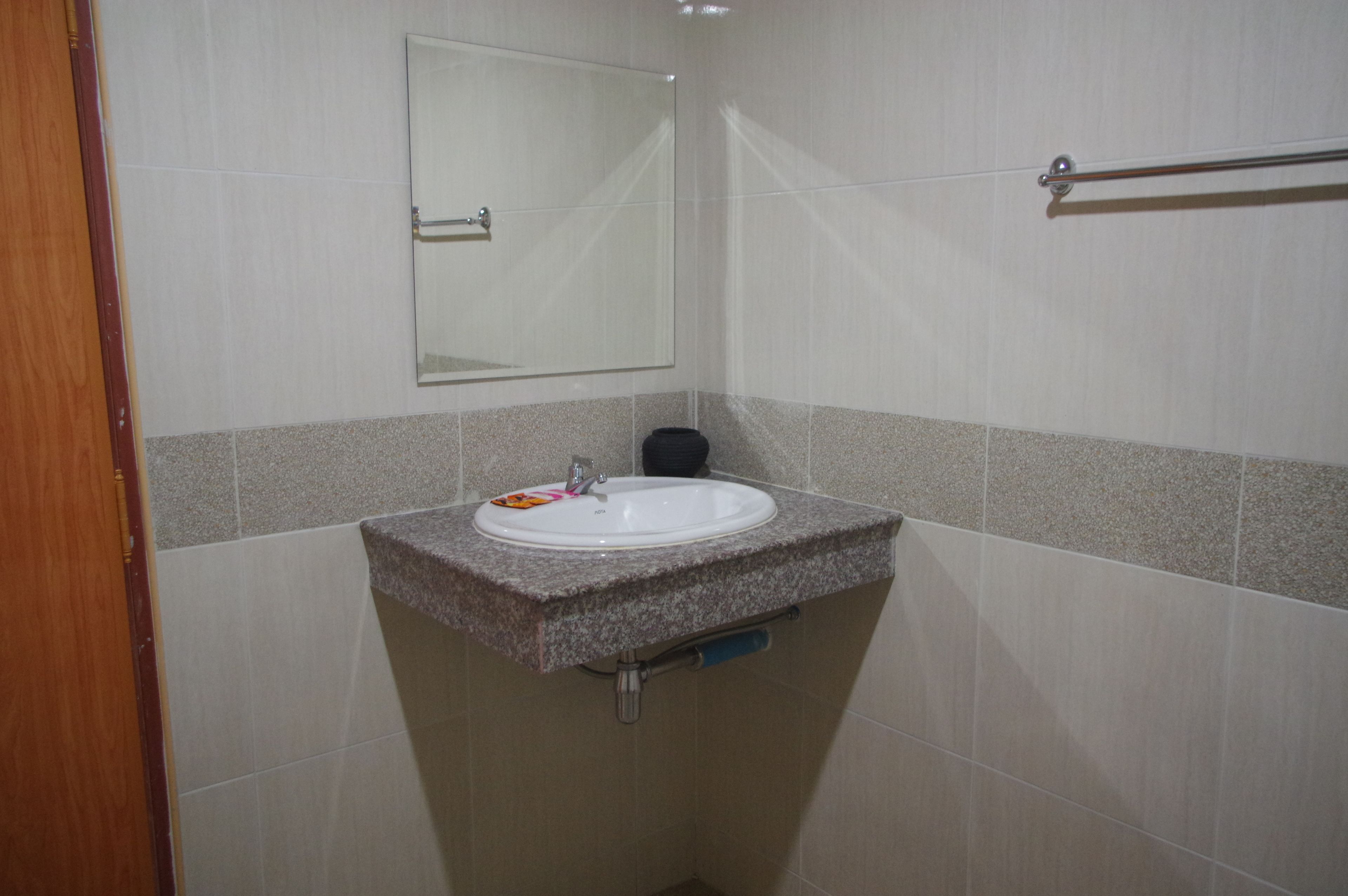 A bathroom with a granite countertop sink, a mirror, and a towel rack.