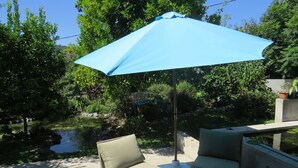 Un espace patio avec deux chaises beiges et un parasol bleu.