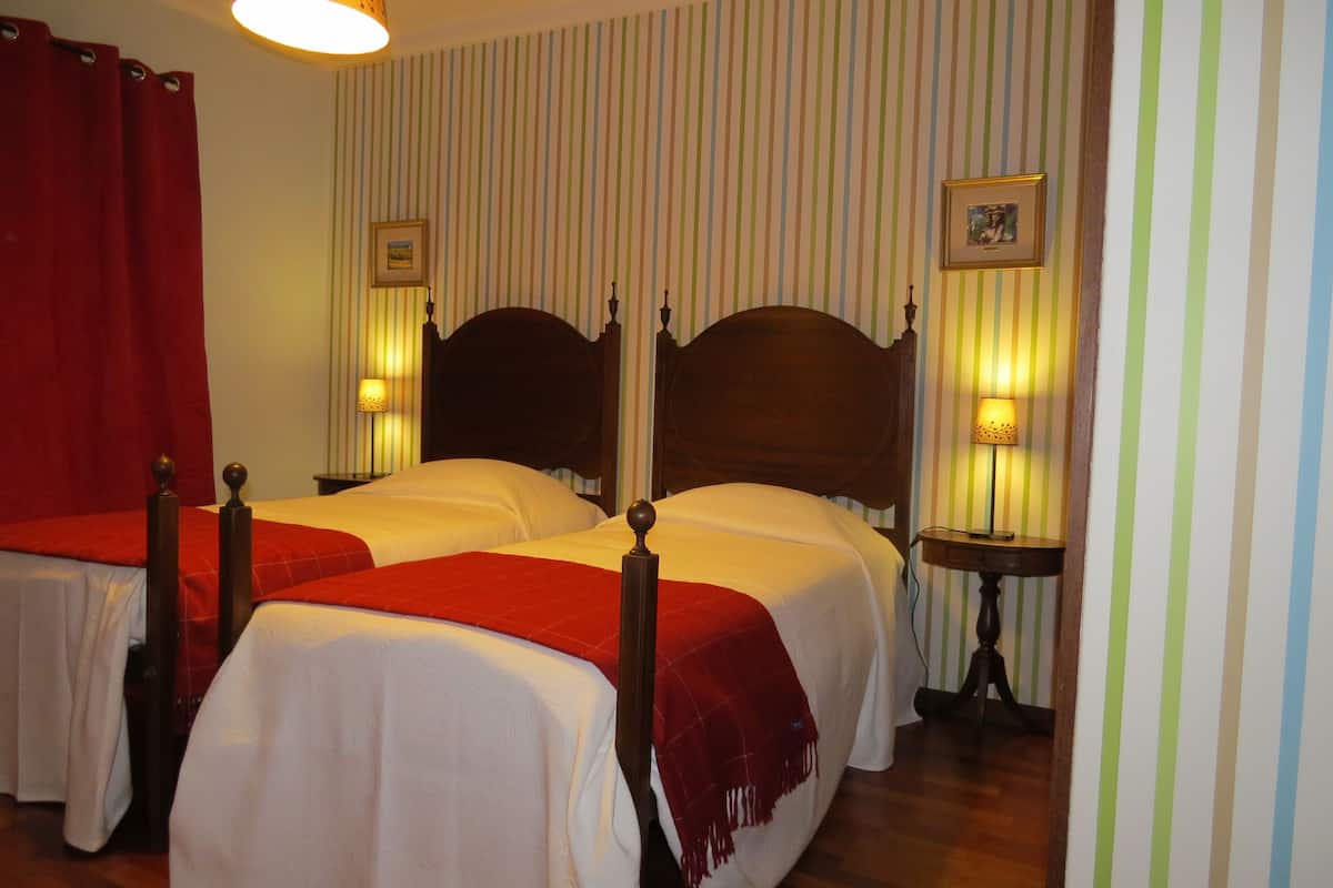 Une chambre d’hôtel avec deux lits, un papier peint à rayures et des lampes de chevet.