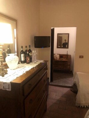 Hotelkamer met een houten dressoir, een flatscreen televisie aan de muur, een spiegel en een kleine badkamer met een houten wastafelmeubel.