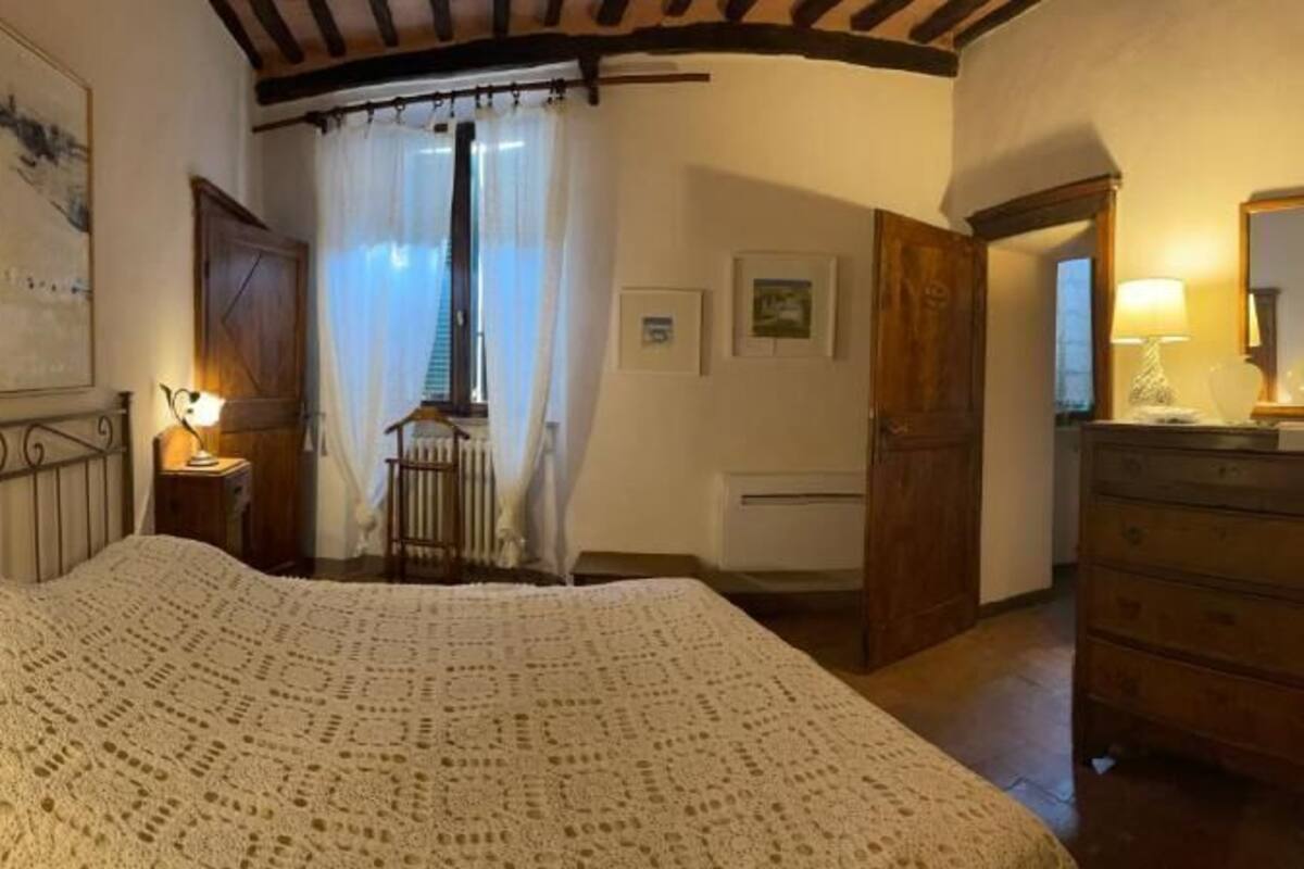 Un dormitorio con cama, cómoda, espejo y ventana con cortinas.