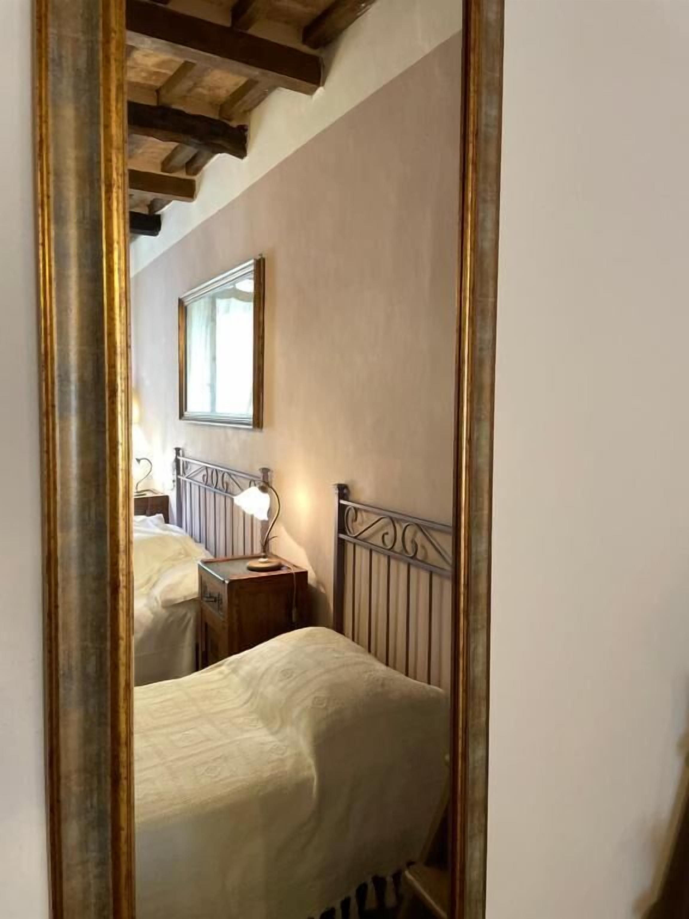 Un dormitorio con una cama, una mesita de noche, una lámpara y un espejo.