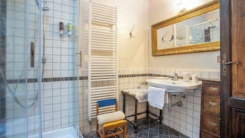 Ein Badezimmer mit Dusche, Waschbecken, Spiegel und einem Holzstuhl.