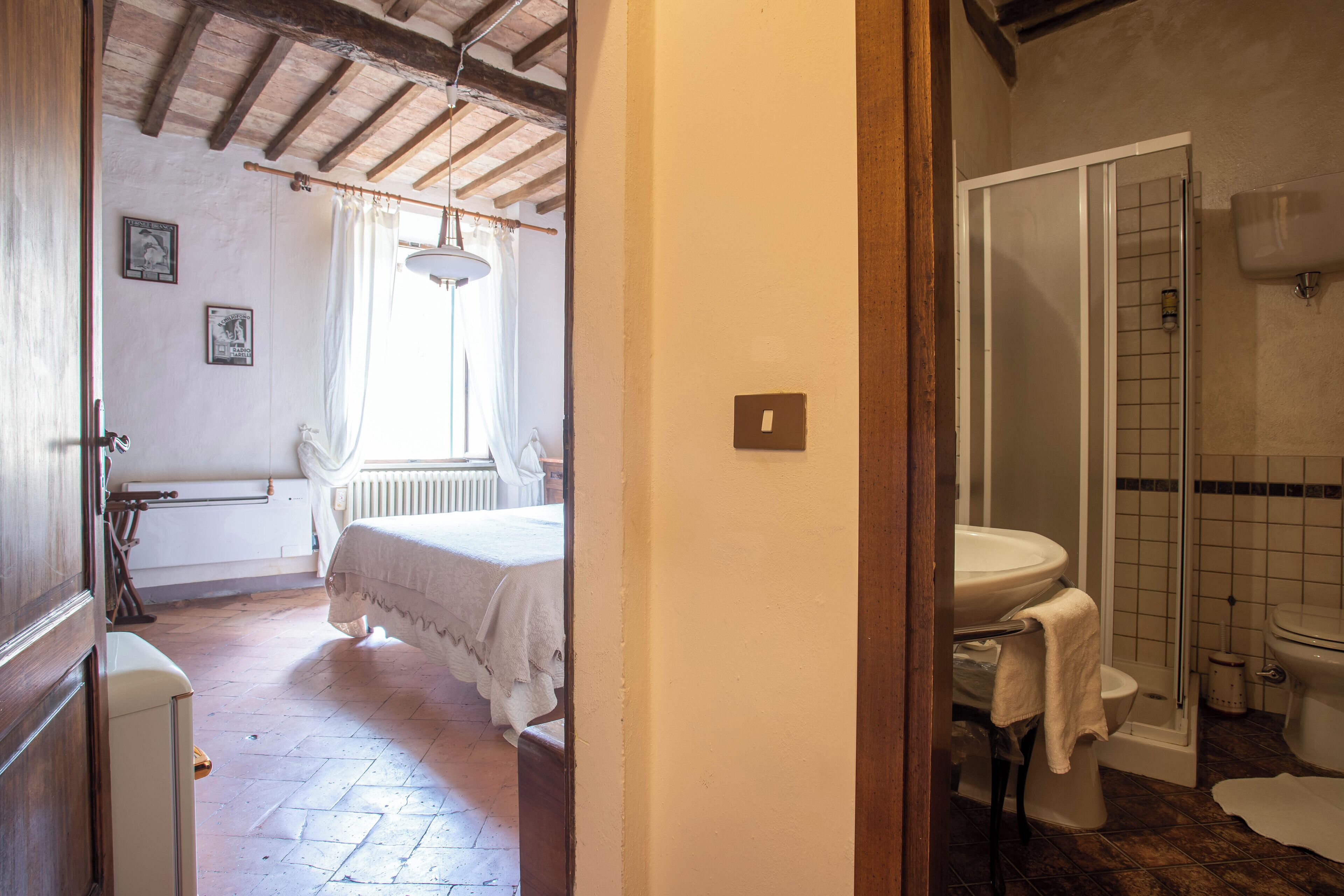 A bedroom with a bed, a radiator, and a window with curtains.