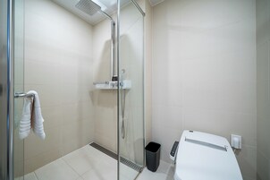 A modern bathroom with a glass shower enclosure, a white sink, and a handheld showerhead.