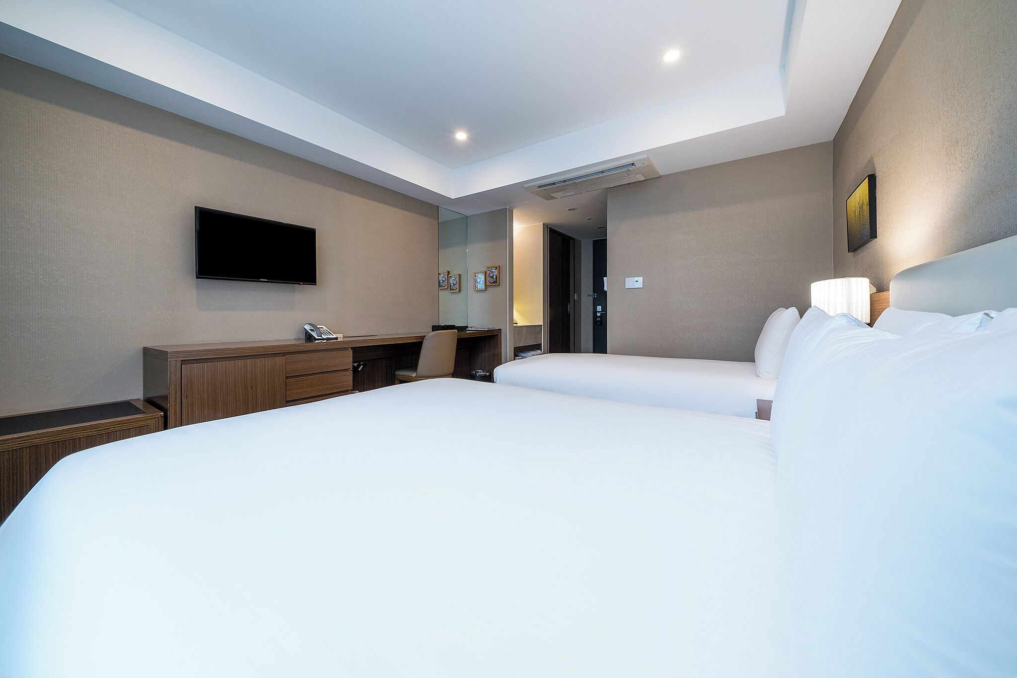 Habitación de hotel con una cama grande, un escritorio, una silla, un televisor de pantalla plana y una puerta que da a otra habitación.