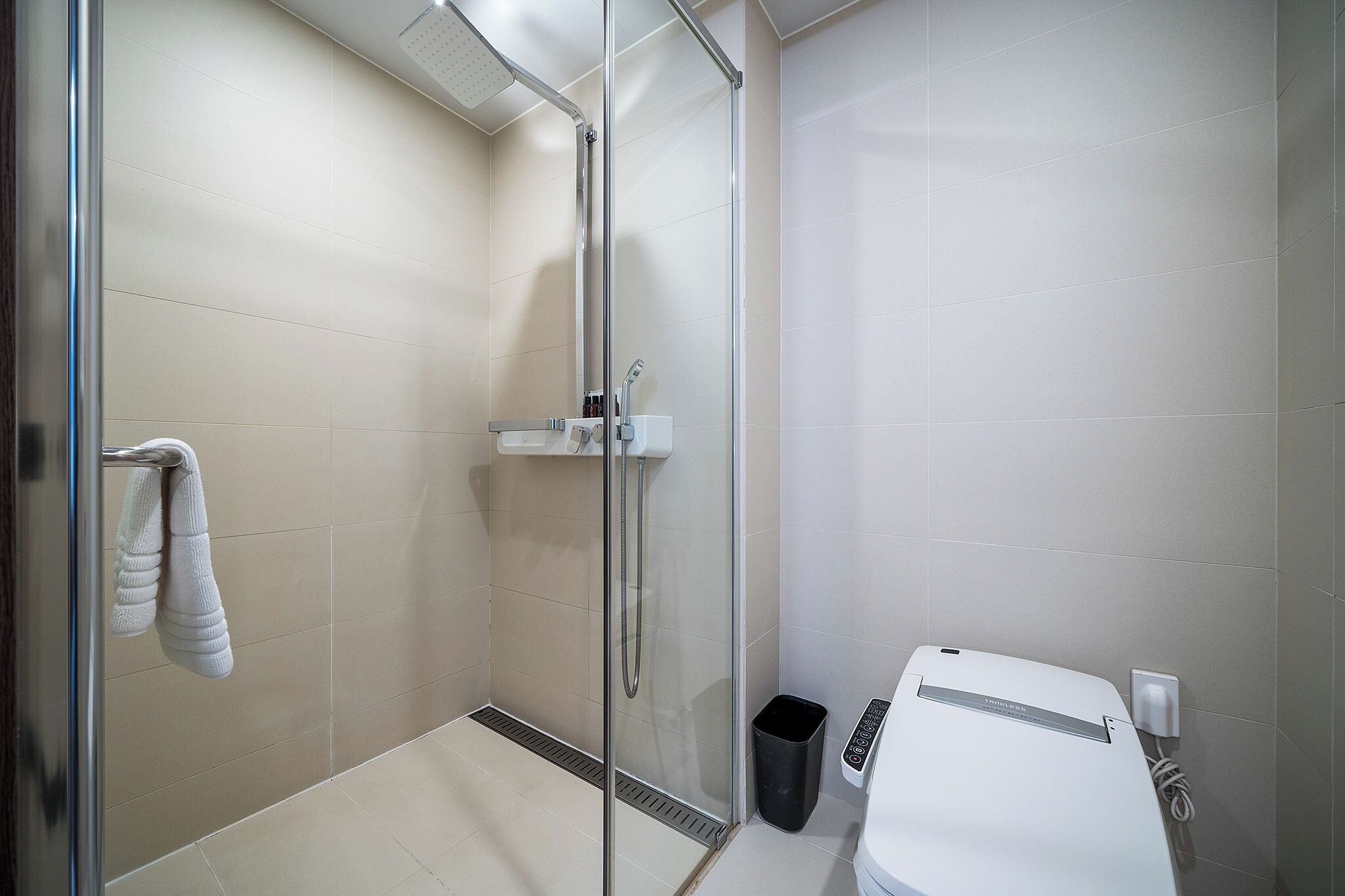 A modern bathroom with a glass shower enclosure, a white sink, and a towel rack.