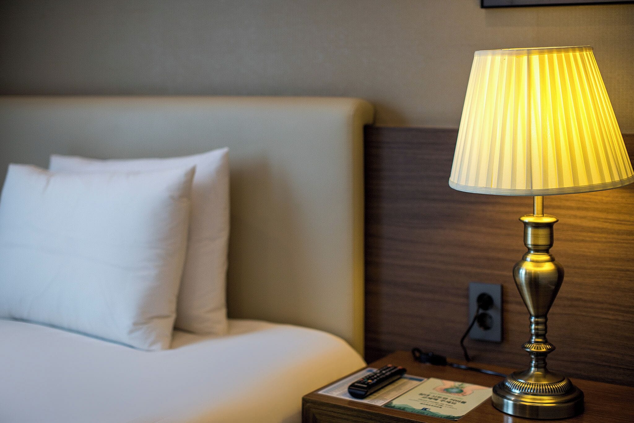 Une chambre d’hôtel avec un lit, une table de chevet avec une lampe et une télécommande.