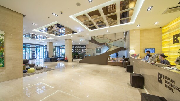 A spacious lobby with a high ceiling, a reception desk, and a staircase leading to upper levels. - Busan Business Hotel (Busan)