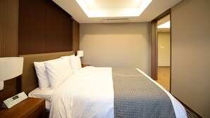 A hotel room with a bed, nightstand, lamp, and a mirror. - Busan Business Hotel (Busan)