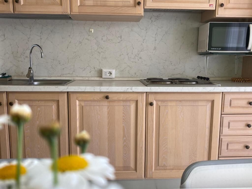 Une cuisine avec des meubles en bois, un évier en acier inoxydable, un four à micro-ondes et une cuisinière.