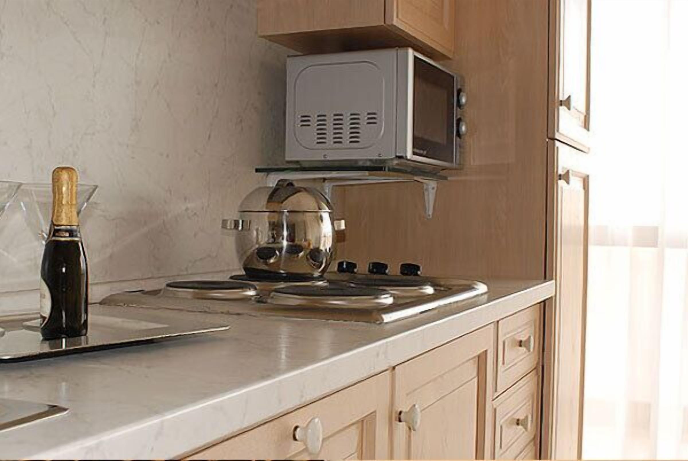 A kitchen with a stove, microwave, and a bottle of champagne.