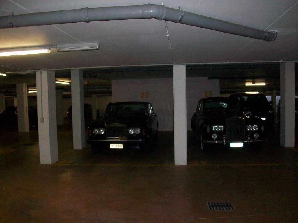 Un parking où sont garées deux voitures anciennes, chacune occupant sa propre place.
