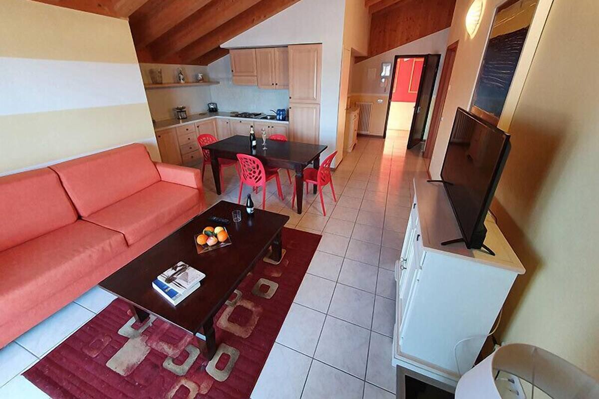 A compact living space with a sofa, a dining table with chairs, a kitchen area, and a television.