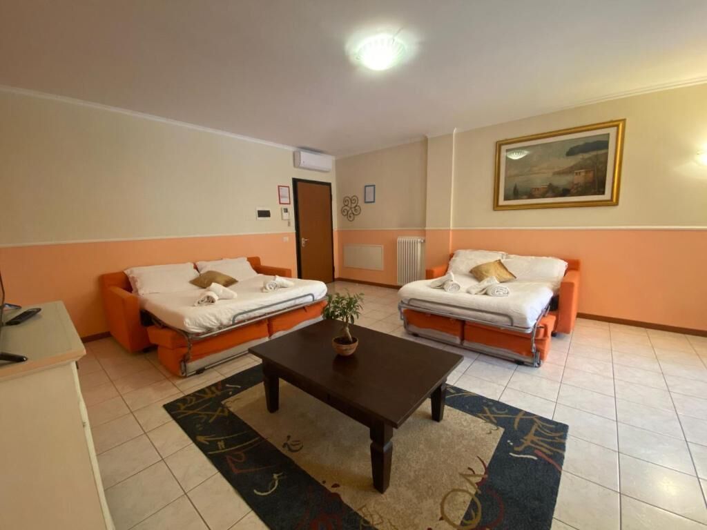 A room with two orange sofas, a wooden table, and a painting on the wall.