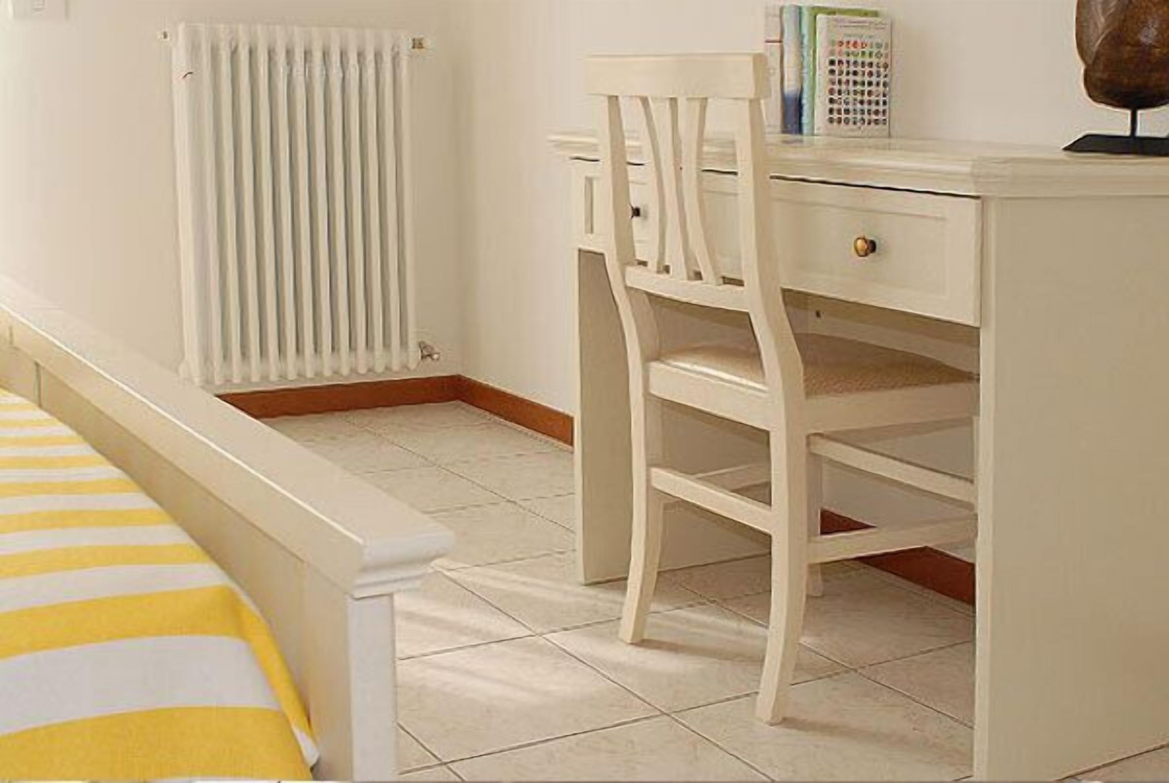 Una habitación infantil con cama, un escritorio blanco y un radiador.