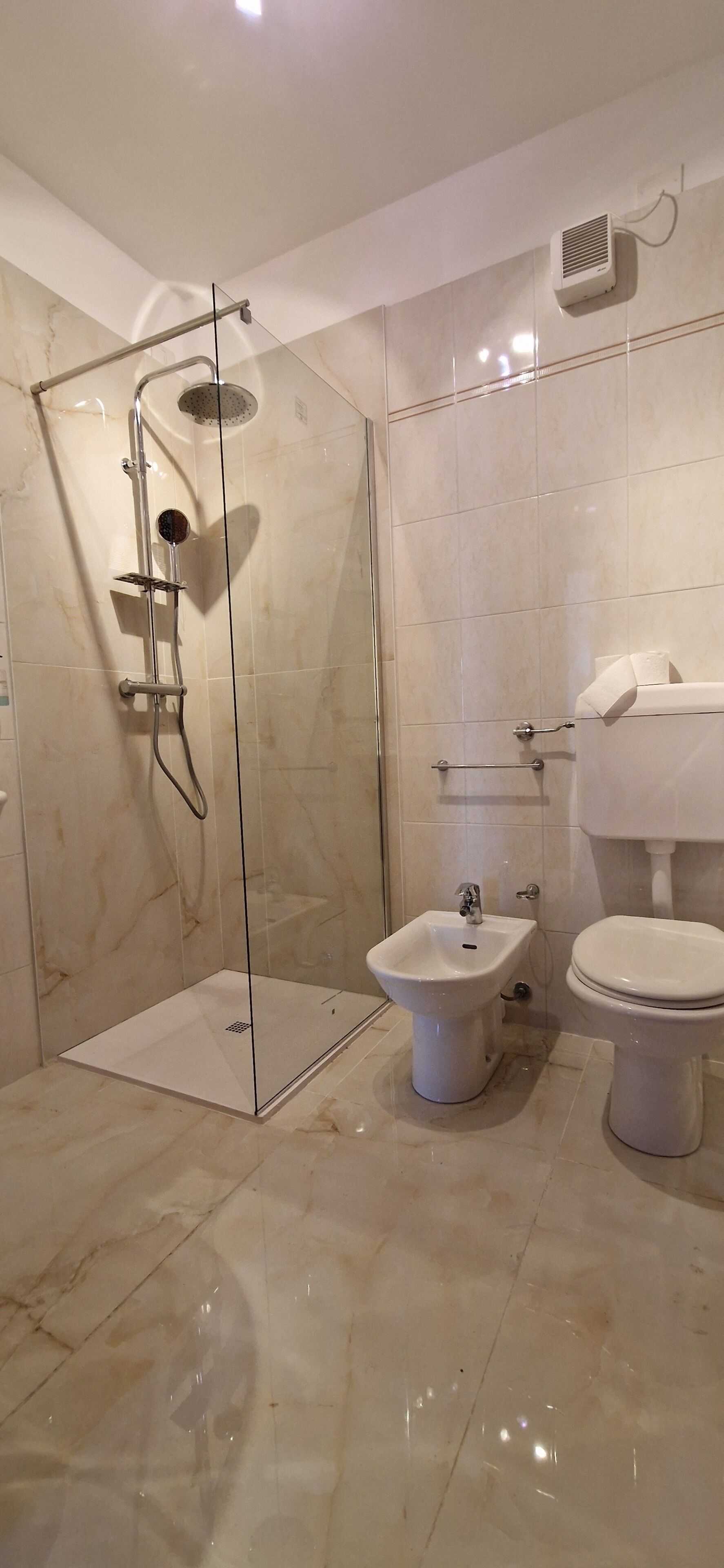 A bathroom with a glass-enclosed shower, a bidet, and a toilet.