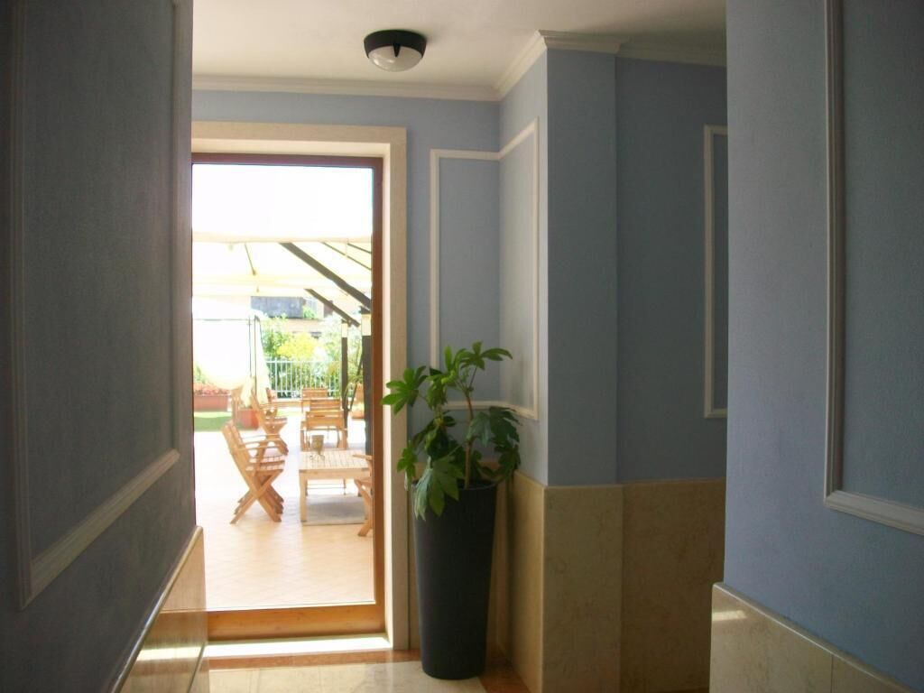 Un pasillo con una planta en maceta y una puerta que da a un patio amoblado.