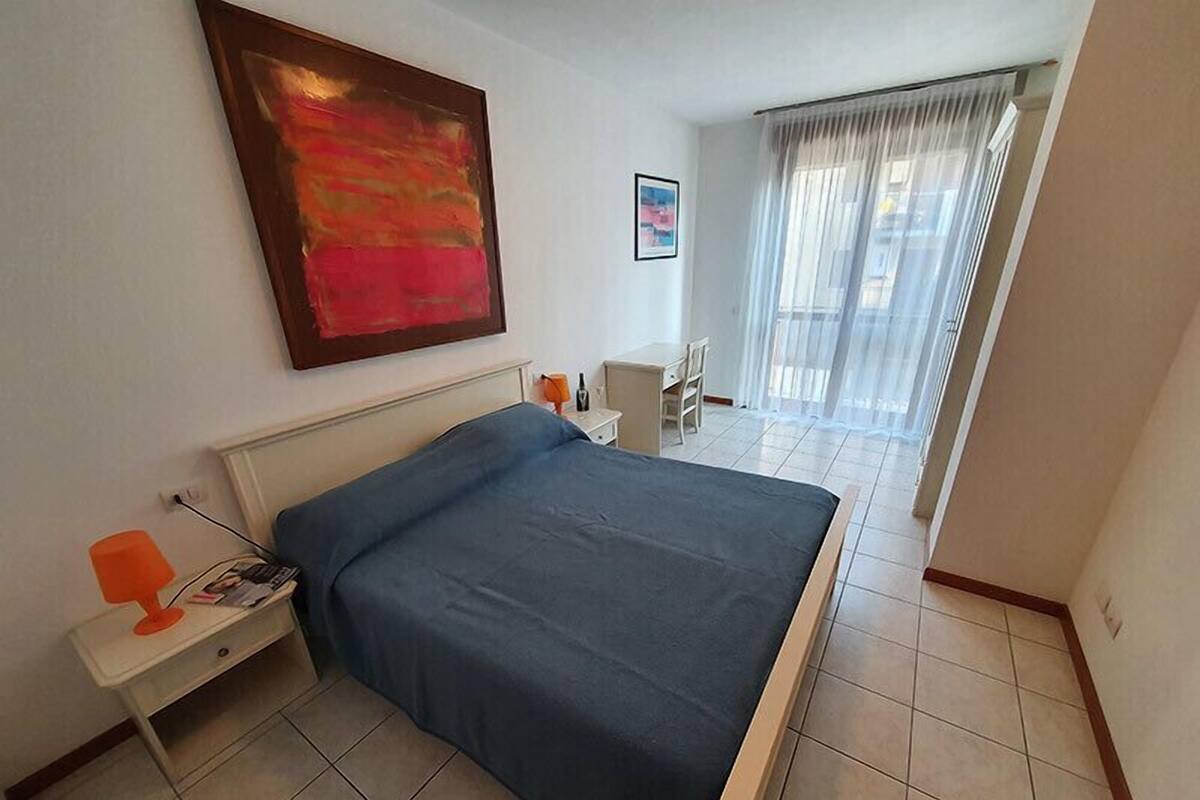 A bedroom with a bed, a desk, and a chair.