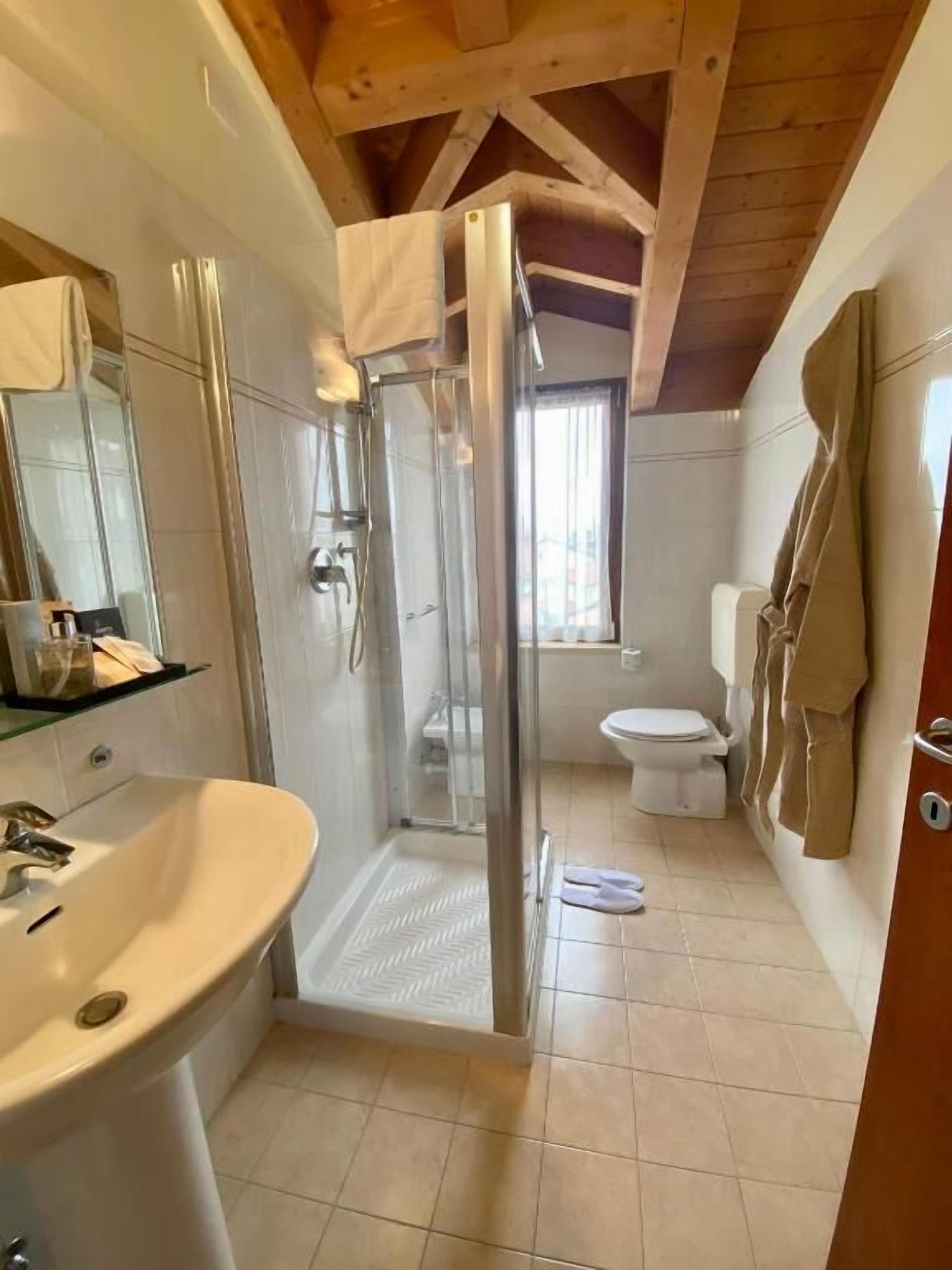 A modern bathroom with a glass-enclosed shower, a white sink, and a toilet.