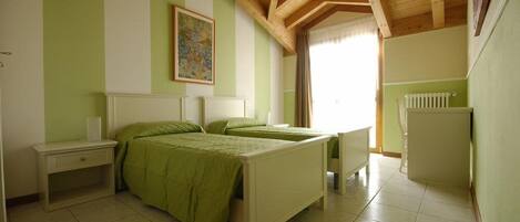 A bedroom with two beds, a nightstand, a dresser, and a radiator.