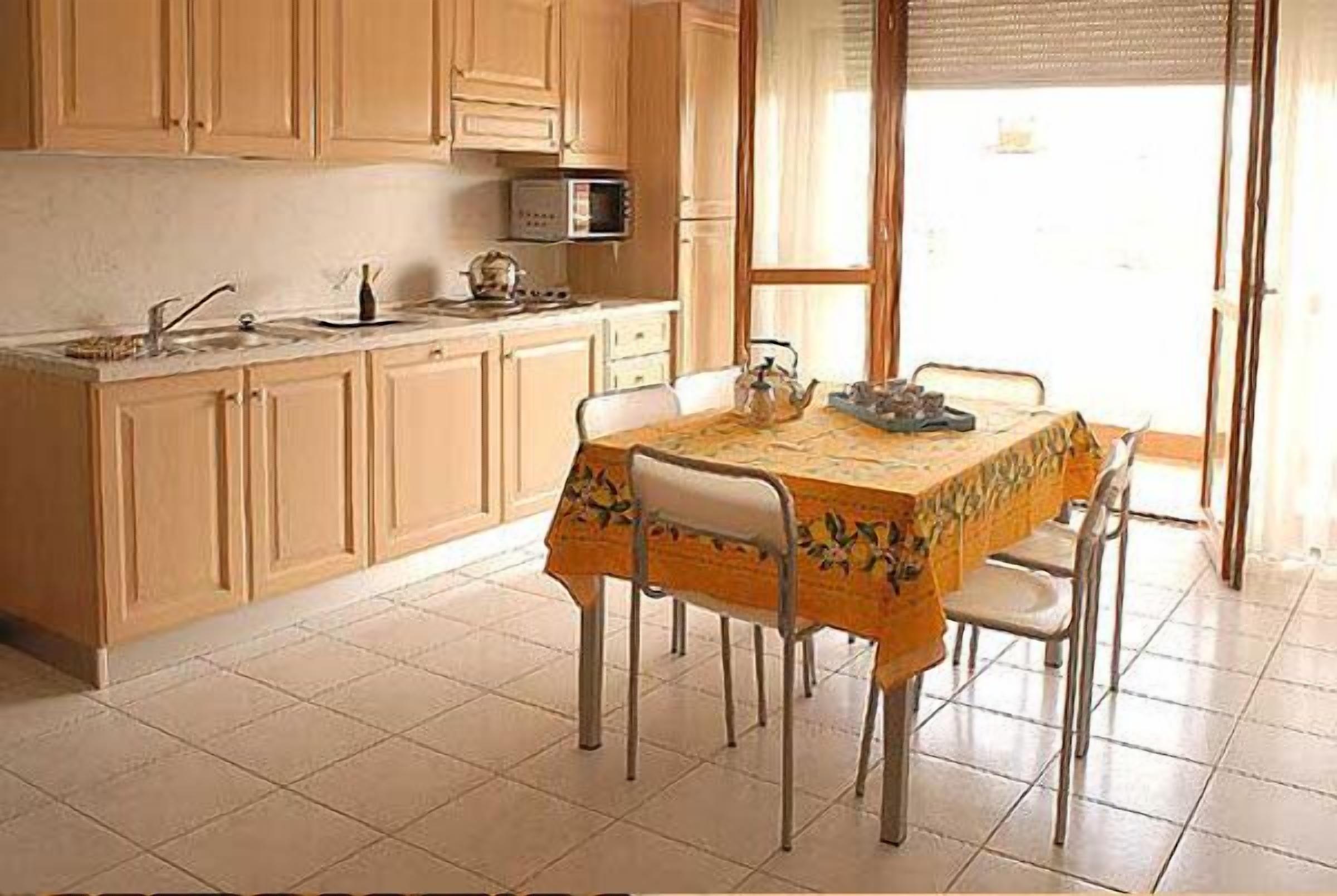 Une cuisine avec des meubles de rangement en bois, un four à micro-ondes, un évier et une table à manger avec des chaises.