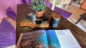 A wooden table with a potted lavender plant, a metal mug, a blue glass, and a book open to a cityscape. - Residence Garda Palace  (Peschiera del Garda)