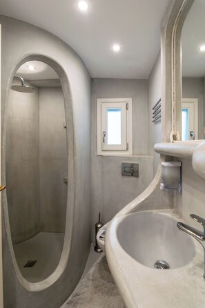 A bathroom with a curved shower, a sink, and a mirror.