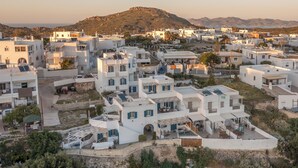 A coastal village with white buildings, some with blue shutters, and a hillside in the background. -  Vivere Houses (Milos)
