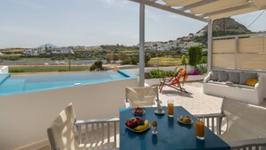 A terrace with a pool, outdoor seating, and a table set with breakfast. -  Vivere Houses (Milos)